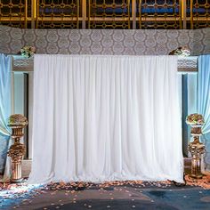 a wedding ceremony setup with white drapes and gold pedestals