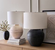 two black and white vases sitting on top of a table next to a lamp