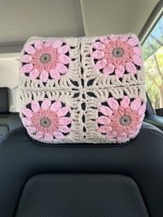 a crocheted pink and white flower on the back of a car seat cushion