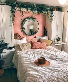 a bedroom with pink walls, white bedding and plants on the headboard is decorated with greenery