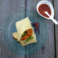 a plate topped with a wrap next to a cup of tea