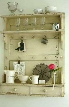 an old wooden shelf with dishes and cups on it