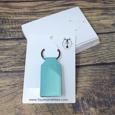 a blue leather keychain sitting on top of a wooden table next to some cards