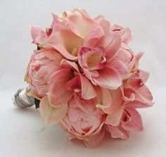 a bouquet of pink flowers sitting on top of a white table next to two wedding rings