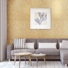 a living room with gold glitter wallpaper and a gray couch in front of a coffee table