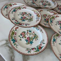 a bunch of plates that are sitting on a counter top with flowers painted on them