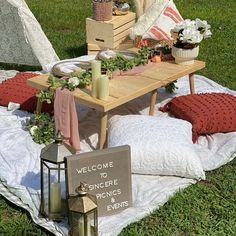 a picnic table set up on a blanket with flowers and candles in front of it