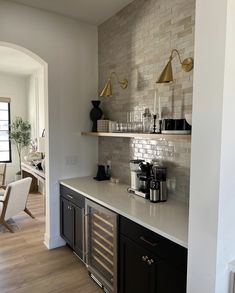 a kitchen with white counter tops and black cabinets, along with open shelving on the wall