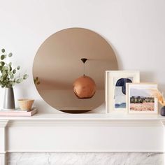 there is a mirror, vase and pictures on the mantle in this living room with white walls