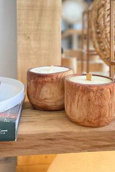 two wooden bowls sitting on top of a table next to a book and candle holder