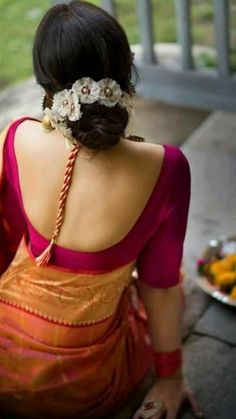 a woman sitting on the ground in front of a plate of food with flowers in her hair