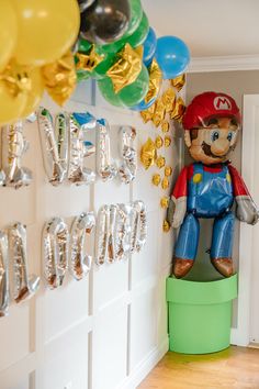 a mario birthday party with balloons, streamers and balloon decorations on the wall behind it