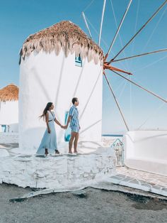 a man and woman holding hands in front of a windmill