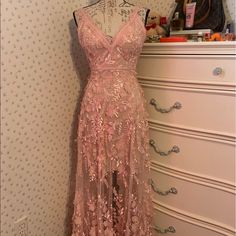 a pink dress is on display in front of a white dresser and wallpapered wall