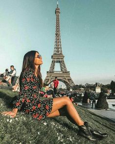 a woman sitting on the grass in front of the eiffel tower, paris