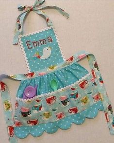 a child's apron with teacups on it and the name emma