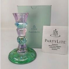 a green glass candle holder sitting next to a box with the label party lite on it