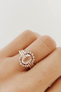 a woman's hand holding a ring with an oval shaped diamond in the center