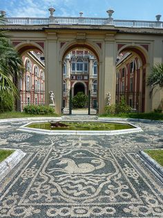 an old building with a fountain in the middle and lots of greenery around it