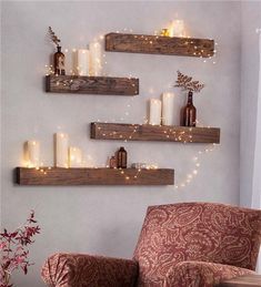 three wooden shelves with candles on them and some lights hanging from the wall behind them