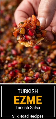 a hand holding a piece of food over a pan filled with beans and other foods