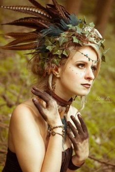 a woman with feathers on her head and hands around her neck, in the woods