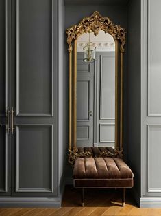 an ornate gold framed mirror sitting on top of a wooden floor next to a bench