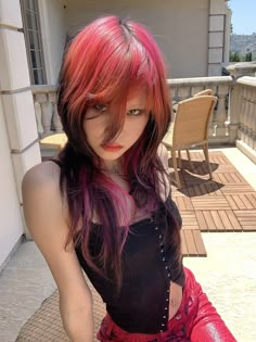 a woman with red hair and black top sitting on a balcony next to a chair