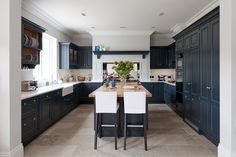 a large kitchen with blue cabinets and white chairs