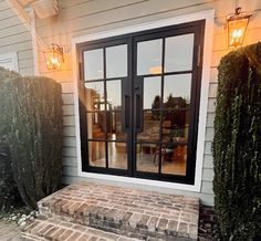 a brick step leading up to the front door of a house with two lights on