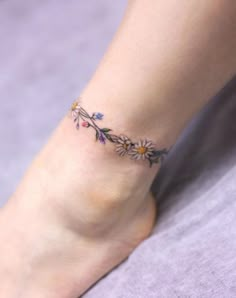 a woman's foot with a flower tattoo on her left ankle and the bottom part of her leg