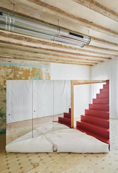 an empty room with red stairs and white walls