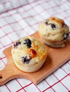 two blueberry muffins on a wooden cutting board