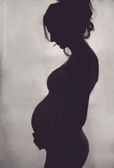 a pregnant woman standing in front of a wall