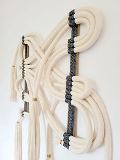 several white and blue cords hanging on a wall with tassels attached to them