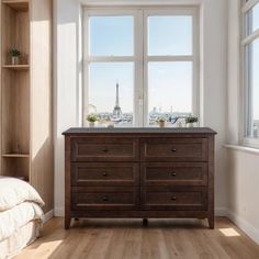 a bedroom with a bed, dresser and window overlooking the eiffel tower in paris