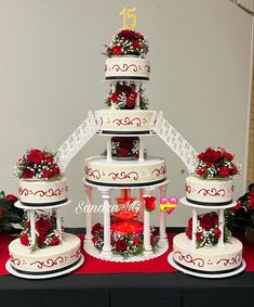 a wedding cake with red roses on top and white icing around the edges, sitting on a table