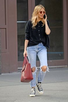 a woman walking down the street talking on her cell phone and holding a handbag