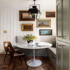 a dining room table with chairs and pictures on the wall above it, along with a bench