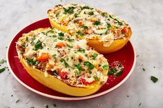 two stuffed squash halves on a red plate with parmesan cheese and fresh herbs