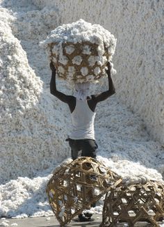 a person carrying something on their head while standing in front of a pile of snow