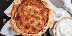 a pie sitting on top of a wooden table next to a bowl of whipped cream