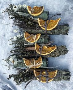 orange slices are arranged on top of dried branches in the snow, with twigs wrapped around them