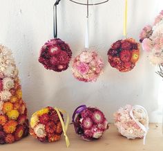 flowers are hanging from the ceiling in front of a white wall and two vases