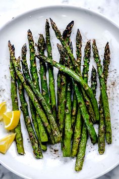 asparagus on a white plate with lemon wedges