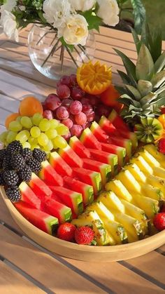 a bowl filled with lots of different types of fruit on top of a wooden table