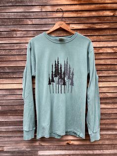 "Long sleeve, green clay tee is printed with my pine trees design in black and grey. This is the perfect top for the nature lover in your life. This is a men's tee but is great for women as well. S: chest 36\", length 27\" M: chest 40\", length 28\" L: chest 44\", length 29 XL: chest 48\", length 29\"" Nature Tees, Green Clay, Tree Shirt, Pine Trees, Weekend Wear, Yoga Tops, Shirt Long Sleeve, Tree Designs, Gift For Dad