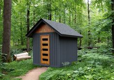 a small outhouse in the middle of a forest with trees and bushes around it