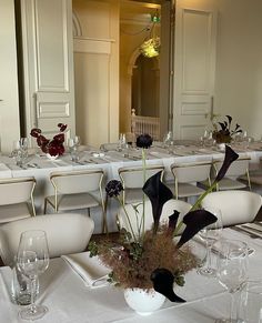 a dining room set up with white tablecloths and place settings for formal dinner