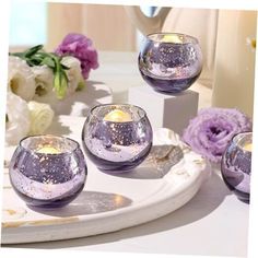 four glass candles are sitting on a plate